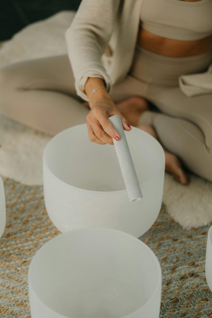 pexels photo 13543280 13543280 A woman in neutral tones playing a crystal singing bowl for meditation and relaxation.