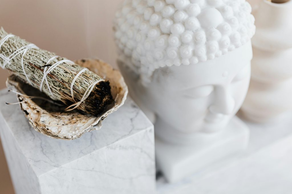 pexels photo 4203096 4203096 From above of sage candle in bowl placed on white marble shelf near plaster Buddha bust and creative shape vase for home decoration